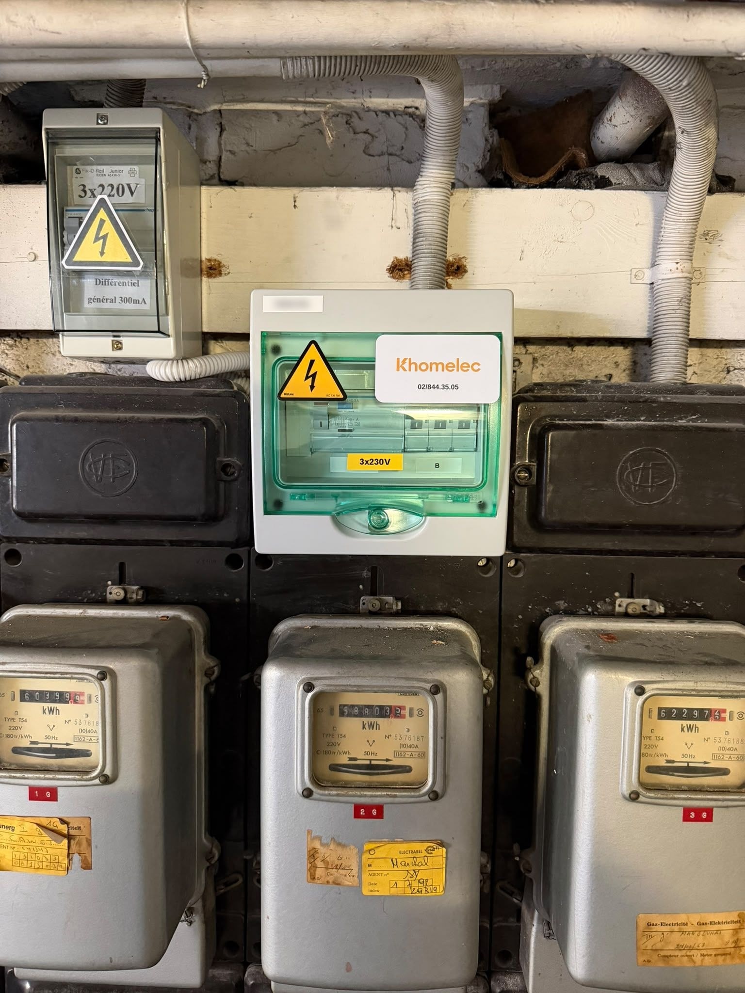 Petit coffret électrique 3x230 V installé entre d’anciens compteurs, dans un local compteurs