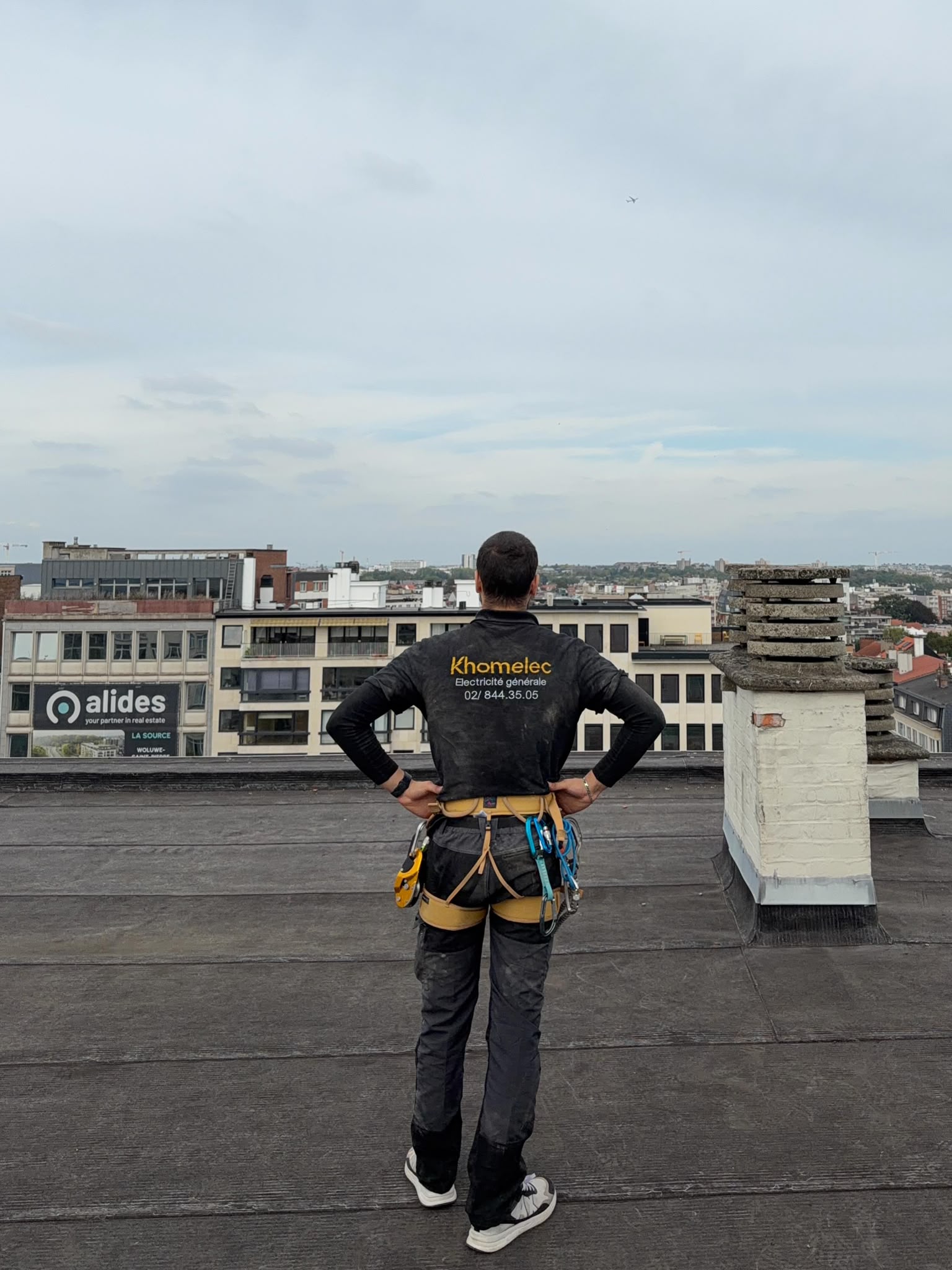 Technicien KHOMELEC équipé d’un baudrier de sécurité sur la toiture d’un bâtiment à Bruxelles